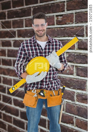 Composite image of handyman holding hard hat and spirit level 15071885