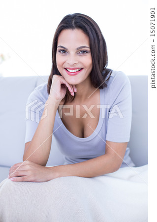 Smiling beautiful brunette sitting on the couch Smiling beautiful brunette sitting on the couch 15071901