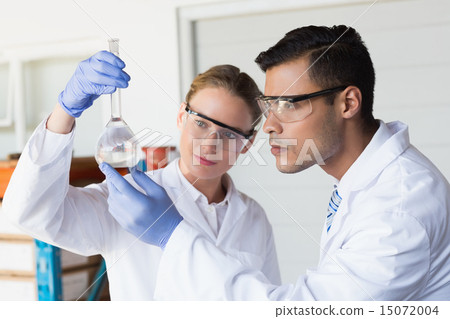 Concentrated scientists looking at beaker 15072004