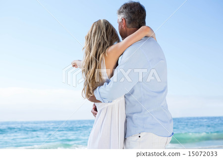 Happy couple standing by the sea and pointing something Happy couple standing by the sea and pointing something 15072033