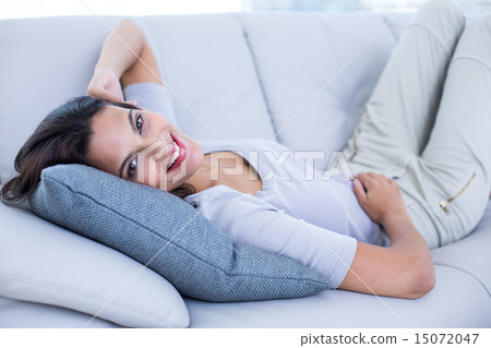 Smiling beautiful brunette relaxing on the couch and looking at Smiling beautiful brunette relaxing on the couch and looking at 15072047