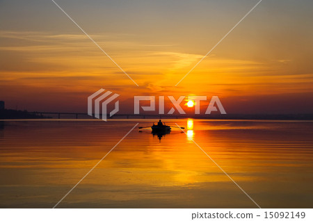 sunset over water surface with small boat 15092149