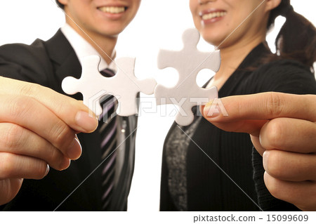 Male and female young businessmen combining pieces of a jigsaw puzzle Male and female young businessmen combining pieces of a jigsaw puzzle 15099609