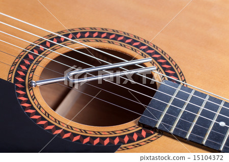 Music tuning fork on acoustic guitar strings 15104372