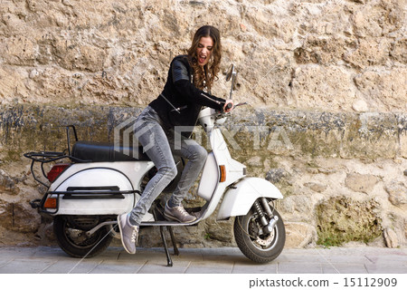 Woman launching a old scooter with pedal 15112909