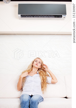 Woman escapes from the heat under the air conditioner 15130997