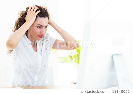 Upset businesswoman sitting at her desk 15140031