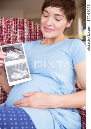 Pregnant woman looking at ultrasound scans Pregnant woman looking at ultrasound scans 15141028