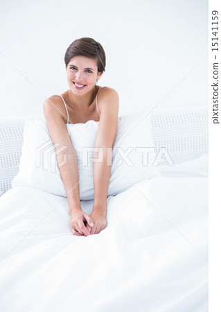 Happy brunette smiling at camera in her bed 15141159