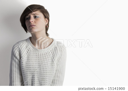 Sad pretty brunette leaning against wall 15141900