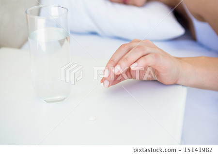 Pretty brunette taking pill on bed Pretty brunette taking pill on bed 15141982