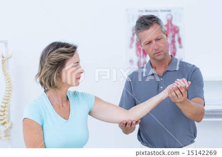 Doctor stretching his patients arm Doctor stretching his patients arm 15142269
