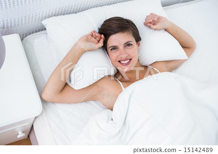 Relaxing woman in her bed smiling at camera Relaxing woman in her bed smiling at camera 15142489