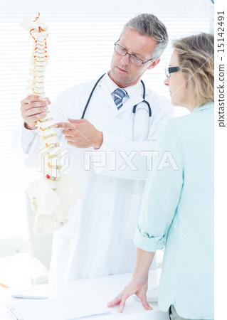 Doctor having conversation with his patient and showing spine mo 15142491