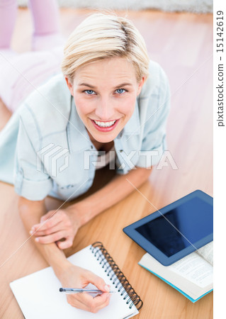 Pretty blonde woman lying on the floor and taking notes while us 15142619