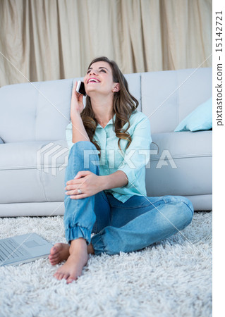 Happy brunette on the phone sitting on the floor 15142721