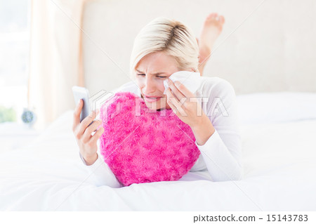 Blonde woman holding her mobile phone and crying 15143783
