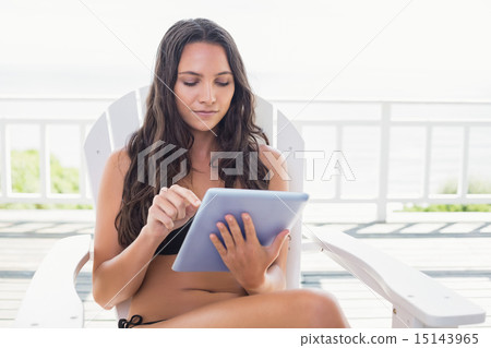 Pretty brunette sitting on a chair and using tablet pc 15143965