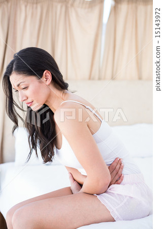 Pretty brunette feeling sick on bed 15143972