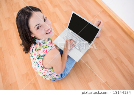 Pretty brunette looking at camera and using laptop on the floor 15144184