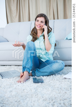 Woman calling while calculating bills with laptop Woman calling while calculating bills with laptop 15144451