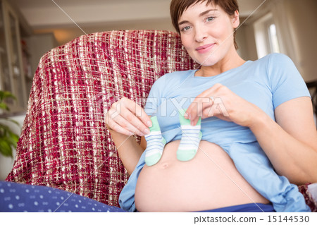 Pregnant woman holding baby shoes over bump 15144530