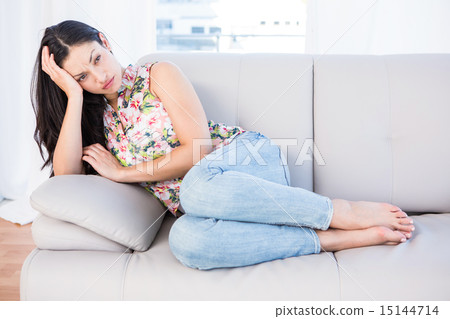Pretty brunette thinking on couch 15144714