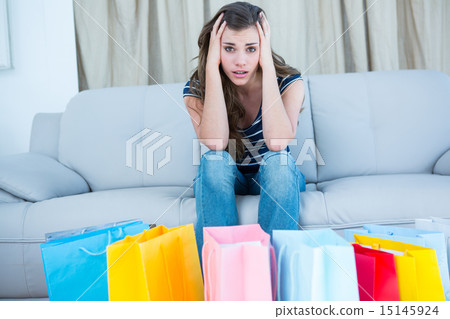 Regretful woman looking at many shopping bags 15145924