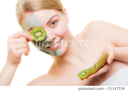 Woman in clay mask on face covering eye with kiwi 15147556