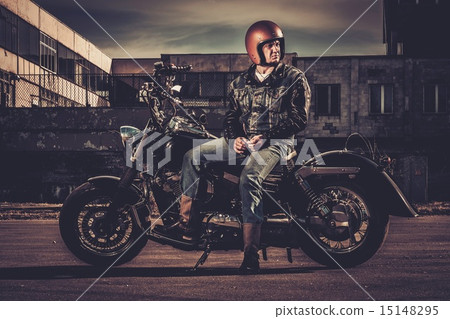 Biker and his bobber style motorcycle on a city streets 15148295