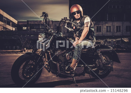 Biker and his bobber style motorcycle on a city streets 15148296