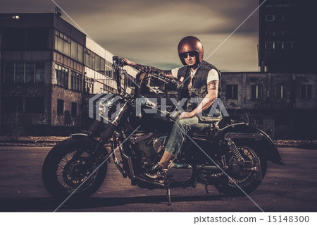 Biker and his bobber style motorcycle on a city streets 15148300
