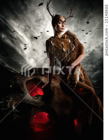 Woman shaman in ritual garment siting on skull Woman shaman in ritual garment siting on skull 15148688