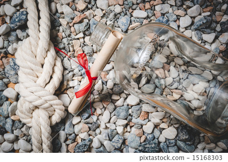 Toned photo of bottle, letter and marine knot lying on seashore 15168303