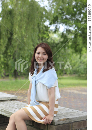 A woman sitting on a park bench 15169049