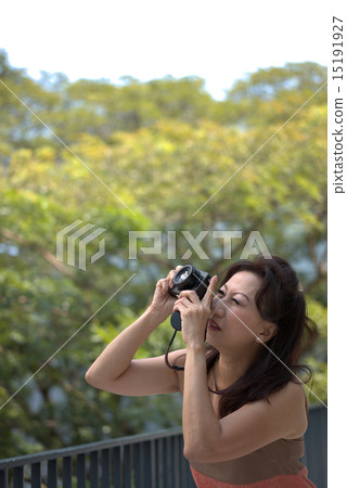 Middle age motherly woman enjoying photography as a hobby Middle age motherly woman enjoying photography as a hobby 15191927