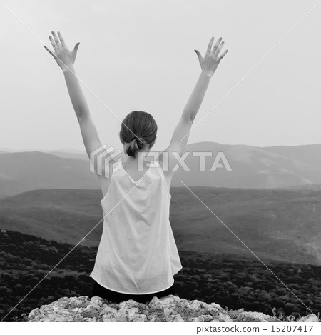 Young woman with arms raised. Girl sitting on a cliff side Young woman with arms raised. Girl sitting on a cliff side 15207417