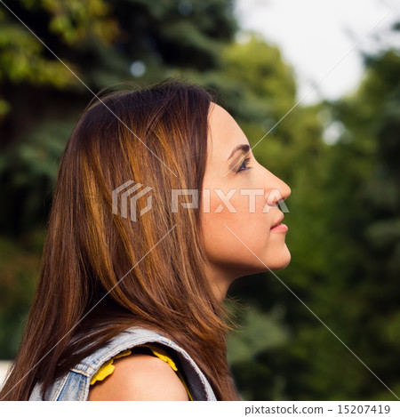 Young women looking up - against background of green park 15207419