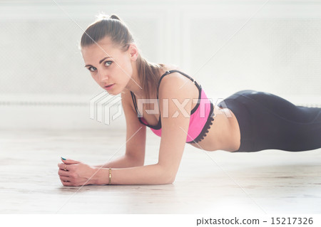 Slim fitnes young girl with ponytail doing planking exercise indoors at home gymnastics 15217326