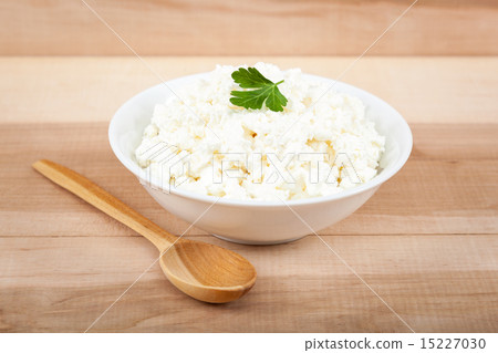 Fresh cottage cheese in a white bowl with spoon. 15227030