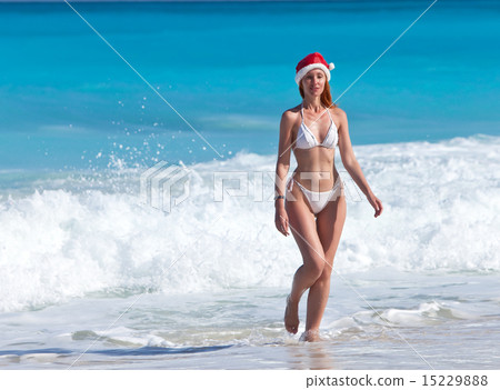 woman in a hat of Santa Claus goes on a beach  15229888