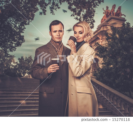 Elegant couple outdoors with cups of hot drink Elegant couple outdoors with cups of hot drink 15270118