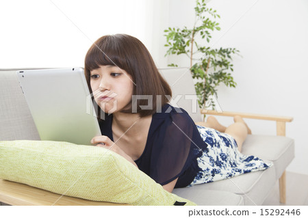 A young woman using a tablet on a sofa 15292446