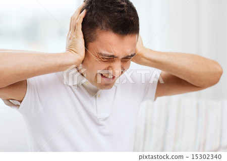 unhappy man closing his ears by hands at home unhappy man closing his ears by hands at home 15302340
