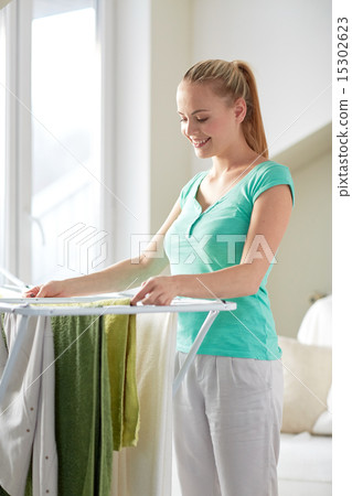 happy woman hanging clothes on dryer at home happy woman hanging clothes on dryer at home 15302623