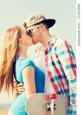 smiling couple with skateboard kissing outdoors smiling couple with skateboard kissing outdoors 15303996
