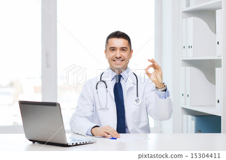 smiling doctor with laptop showing ok in office smiling doctor with laptop showing ok in office 15304411