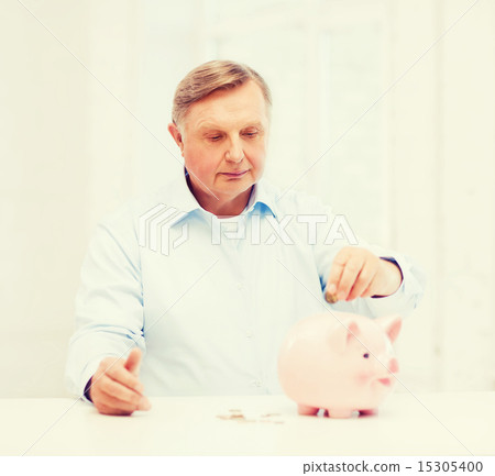 old man putting coin into big piggy bank old man putting coin into big piggy bank 15305400