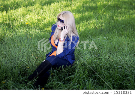 the girl tells by phone on a lawn the girl tells by phone on a lawn 15318381