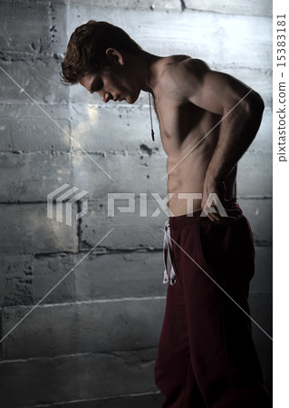 Handsome athlete with a naked torso adjusts his pants. The pictu 15383181